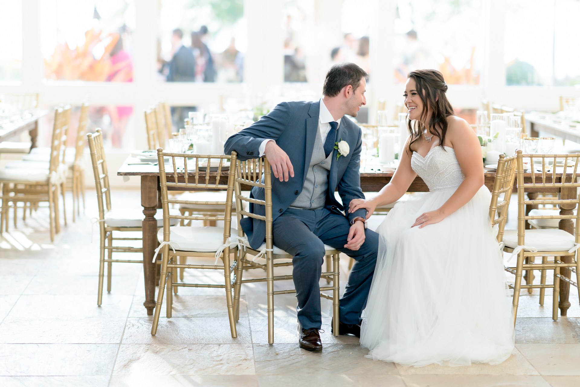Bride and groom smiling together among reception chairs