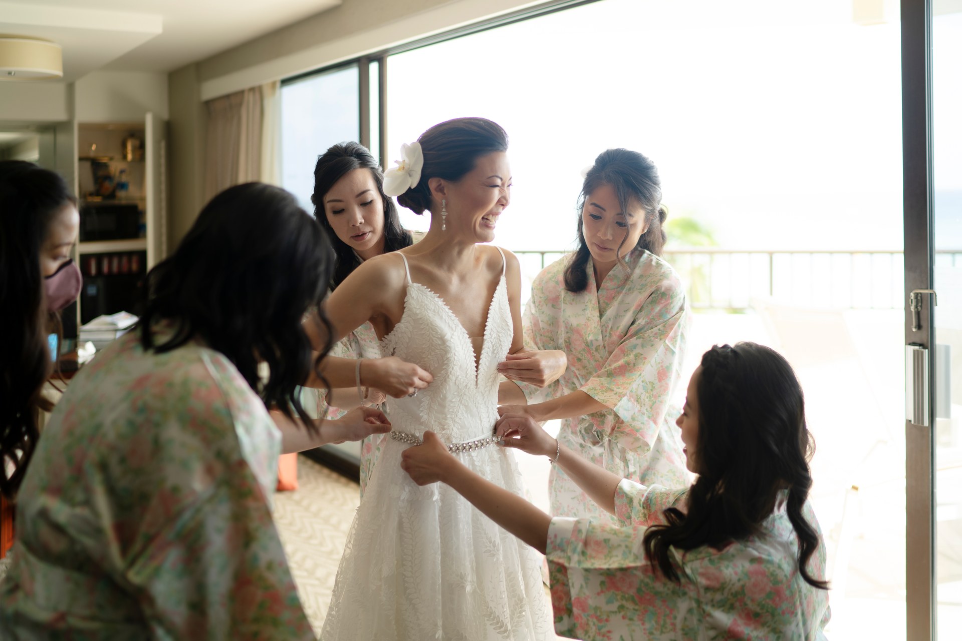 Family helping the bride get ready beside a window