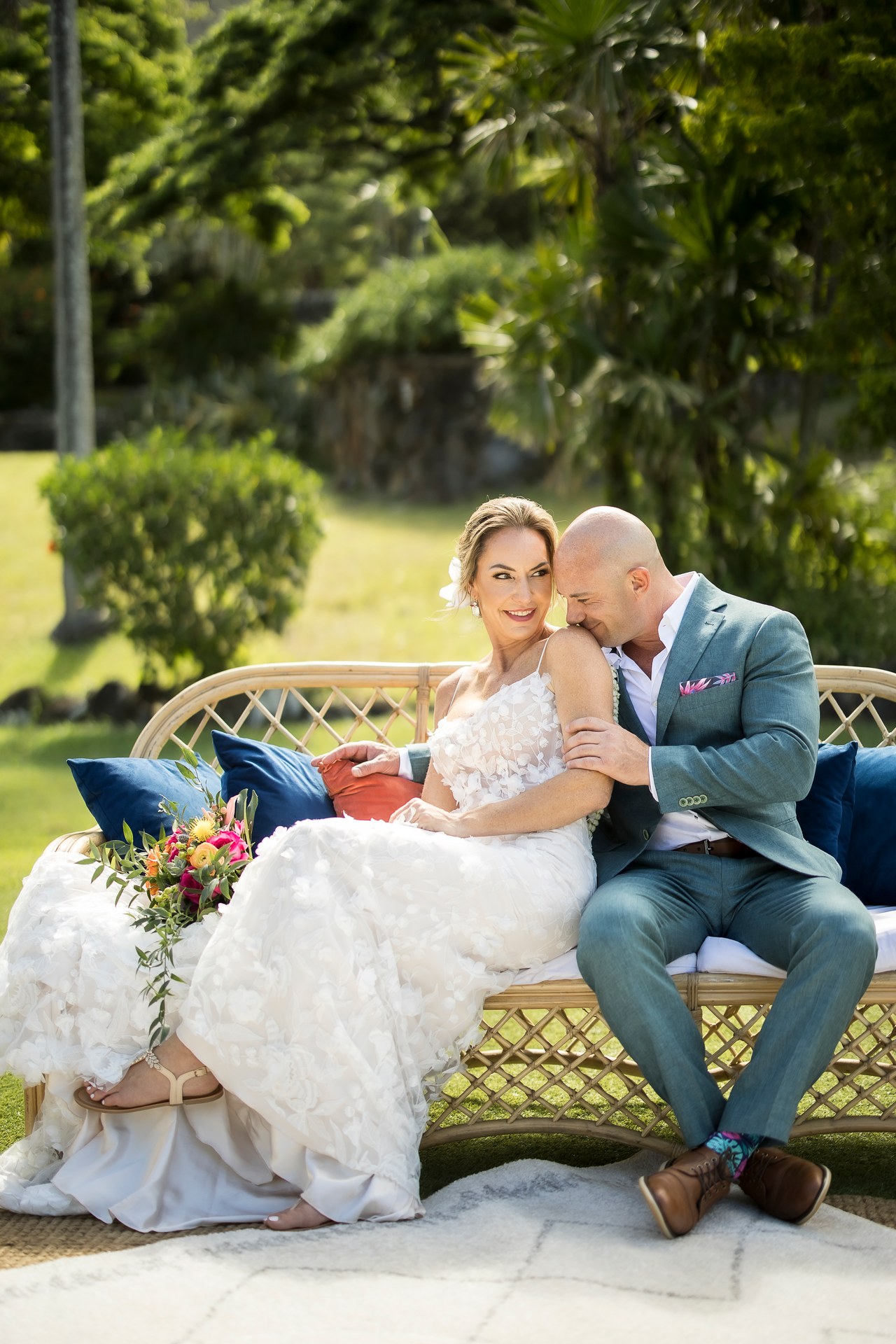 Bride and groom sharing an affectionate moment on a garden sofa